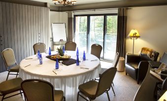 a conference room with a white table surrounded by chairs and blue bottles , along with a window and a chandelier at Hotel-Musee Premieres Nations