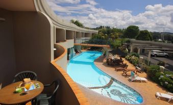 a rooftop pool surrounded by chairs and tables , with a beautiful view of the city in the background at Breakers Motel