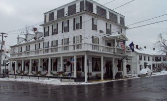 a large white building with a balcony and several flags is situated on a snow - covered street at Hotel Strasburg