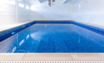 an empty swimming pool with blue water , surrounded by white walls and a white ceiling at The Dragon Hotel