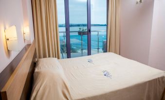 a bed with a white blanket and two blue lobsters on it , next to a window that overlooks a body of water at Hotel Bijou