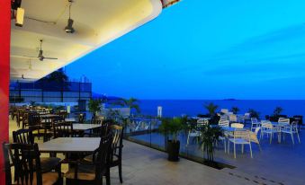 restaurant with a waterfront view, offering seating options both indoors and outdoors, perfect for enjoying the scenic ambiance during evening hours in a city setting at Hotel Sentral Seaview @ ​Beachfront