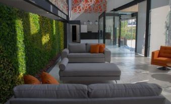 a modern living room with gray couches and orange pillows , surrounded by a green wall at Hangar Inn Guadalajara Aeropuerto
