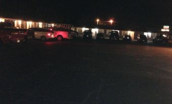 a nighttime scene of a parking lot filled with numerous cars , illuminated by street lights at Village Inn