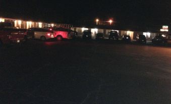 a parking lot with multiple cars parked , illuminated by bright lights , and surrounded by buildings at Village Inn