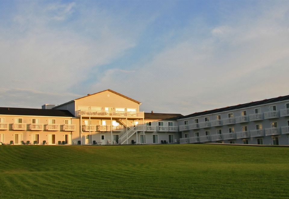 a large building with a grassy field in front and stairs leading up to it at Château Madelinot