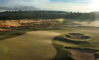 aerial view of a golf course with sand traps and mountains in the background during sunset at Wilderness Club