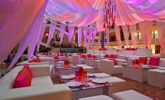 a lavishly decorated banquet hall with white couches and chairs , pink and purple chandeliers , and a chandelier at Four Seasons Hotel Cairo at the First Residence