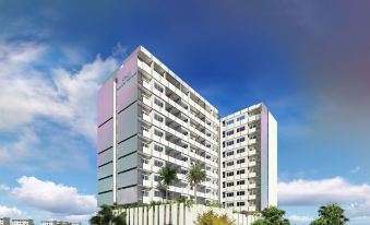 a tall building with many windows is surrounded by trees and a building with a rainbow in the sky at Neelkanth Sarovar Premiere