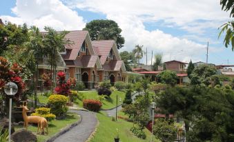 a lush green hillside with a group of houses surrounded by lush greenery , including trees , bushes , and flowers at Khas Parapat