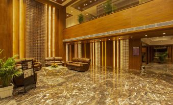 a luxurious hotel lobby with marble floors and walls , featuring a large chandelier and several couches at Sarovar Portico, Somnath