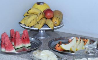 a variety of fruits , including bananas , apples , and oranges , placed on a dining table in a kitchen setting at Oasis Hotel