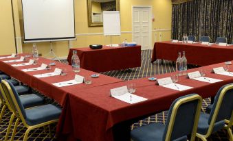 a conference room set up for a meeting , with several tables and chairs arranged in a semicircle at Buckatree Hall Hotel