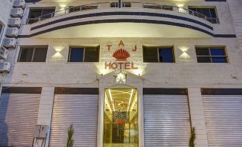 a large hotel building with a red sign on the front , located in a city at Taj Hotel