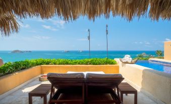 a rooftop patio overlooking the ocean , with two lounge chairs and a bottle of beer on the table at Cala de Mar Resort & Spa Ixtapa