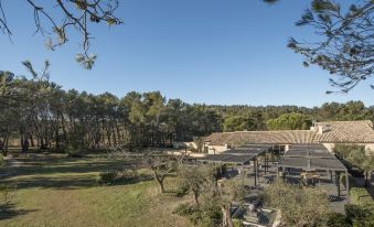 a rural setting with a large barn surrounded by trees and grass , providing a picturesque view at Domaine la Pierre Blanche