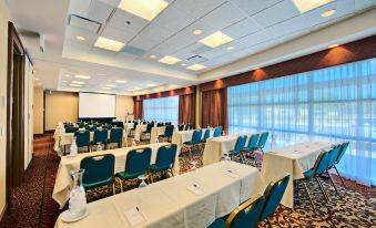 a large conference room with rows of chairs arranged in a semicircle , and a projector screen mounted on the wall at Hilton Garden Inn Laramie