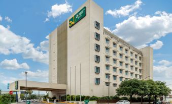 a large , white building with a green sign on top and cars parked in front at Quality Inn Monterrey la Fe