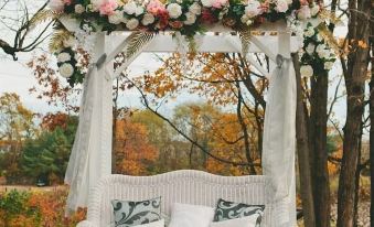 a white wicker wedding bed in the middle of a forest , surrounded by trees and autumn leaves at Black Swan Inn