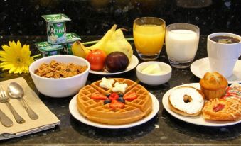 a table is set with a variety of breakfast foods , including waffles , fruit , and milk at Seams Like Home B&B