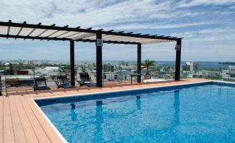 a rooftop pool surrounded by lounge chairs and umbrellas , with a view of the city in the background at Four Points by Sheraton Veracruz