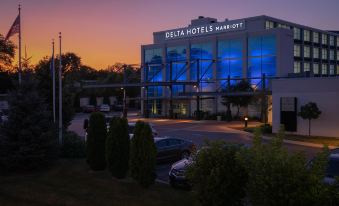 "a large building with a blue sign that reads "" delta hotels "" and cars parked in front" at Delta Hotels by Marriott Milwaukee Northwest