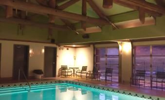 an indoor swimming pool surrounded by wooden beams , with lounge chairs placed around it for relaxation at Quartz Mountain Resort