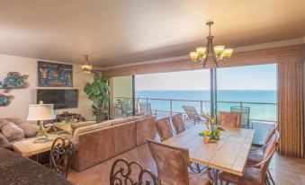 a spacious living room with a dining table and chairs , along with a view of the ocean at Las Palomas Beach & Golf Resort