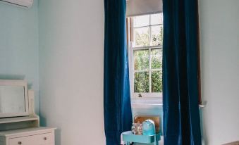 a cozy bedroom with a blue window , curtains , and a bed , giving it a comfortable and inviting atmosphere at Terroir Auburn