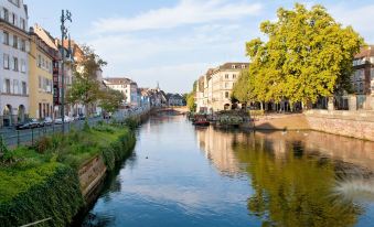 a river flows through a city with buildings on either side and a clear blue sky at Hotel Suisse