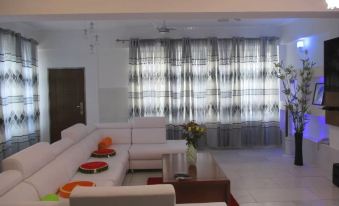 a modern living room with white couches and chairs arranged around a coffee table , creating a cozy atmosphere at Luxury Apartment