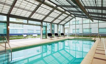 a large indoor swimming pool surrounded by glass walls , with several lounge chairs placed around it at Sheraton Valley Forge King of Prussia