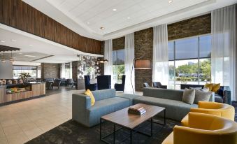 a large , modern hotel lobby with various seating options , including couches and chairs , as well as a dining area at Hyatt Place Fresno