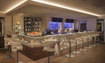 a modern restaurant with a bar area , where several people are seated and enjoying their meals at Delray Sands Resort