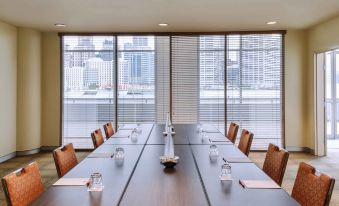 a long conference table with chairs and a vase in the center , surrounded by large windows at Ibis Sydney Darling Harbour