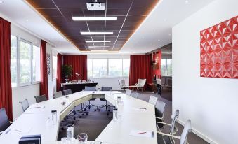 a large conference room with a long white table and multiple chairs arranged for a meeting at Novotel Avignon Nord