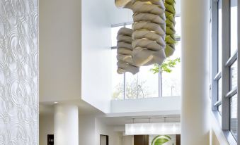 a modern hotel lobby with white columns , large windows , and hanging circular decorations on the walls at Element Vancouver Metrotown
