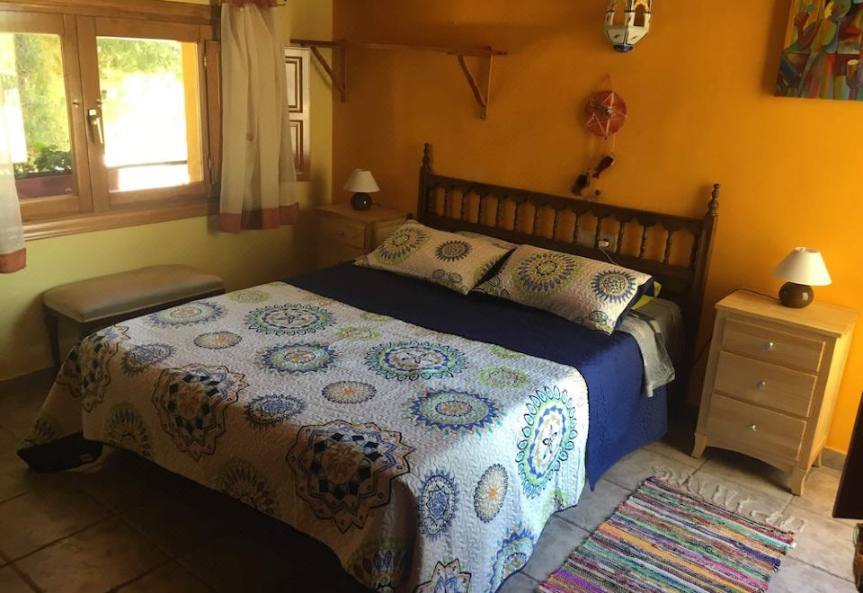 a large bed with a blue and white comforter is in a room with orange walls at La Esencia