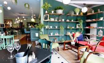 a modern dining room with blue walls , wooden furniture , and various plants , as well as a dining table set for a meal at Ibis Nantes Saint-Herblain