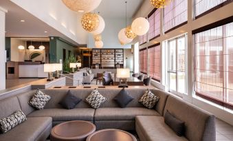 a modern lounge area with gray couches and chairs , as well as pendant lights hanging from the ceiling at Element Lexington