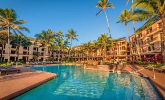 a resort with a large pool surrounded by palm trees , and several people enjoying their time in the water at Sheraton Kauai Coconut Beach Resort