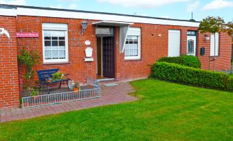 a brick house surrounded by a well - maintained garden , with a car parked in the driveway at Gila