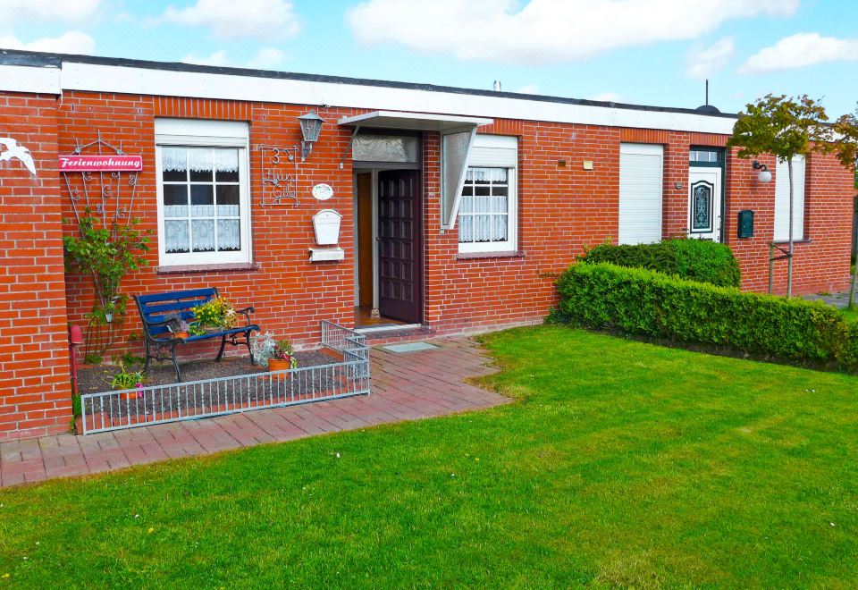 a brick house surrounded by a well - maintained garden , with a car parked in the driveway at Gila