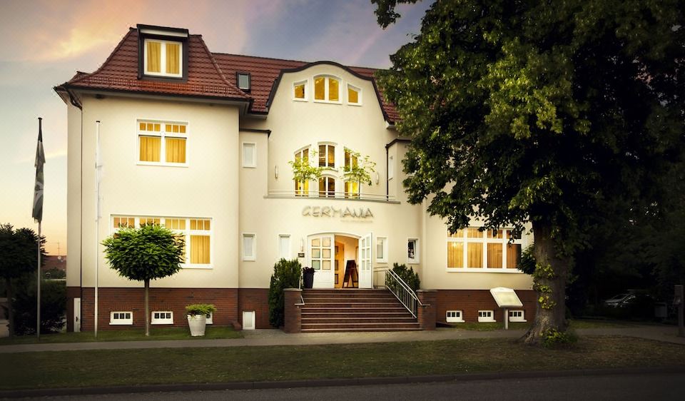 a white building with a red roof , located on a street in a small town at Hotel Germania