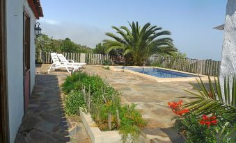 a backyard with a pool surrounded by a patio , and a deck area with chairs and a table at Domi