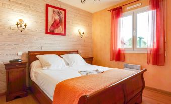 a cozy bedroom with a wooden bed , white sheets , and orange blankets , lit by two wall - mounted lamps at L'Olivier