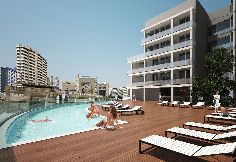 a large swimming pool is surrounded by lounge chairs and a tall building in the background at Hotel Bristol 4 Sup