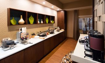 a modern kitchen with wooden floors , white countertops , and various cooking utensils on display , including pots and pans at Holiday Inn & Suites Bothell