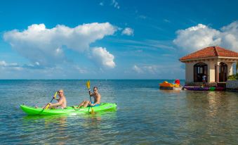 a group of people , including a man and a woman , are kayaking in the ocean , surrounded by water and a building at Coco Beach Resort