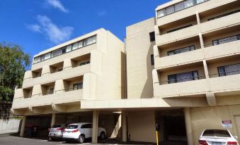 a three - story building with a parking lot in front of it , and several cars parked outside at St Ives Apartments